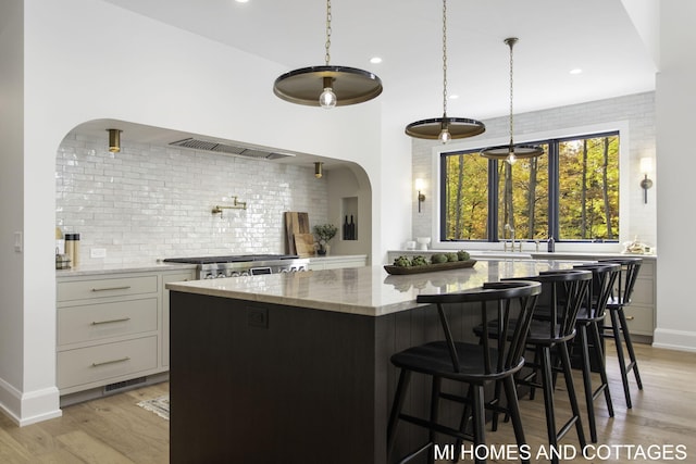 kitchen featuring light hardwood / wood-style floors, a center island, light stone counters, and white cabinets