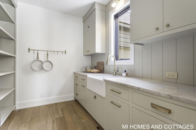 kitchen featuring sink, light hardwood / wood-style flooring, and light stone counters