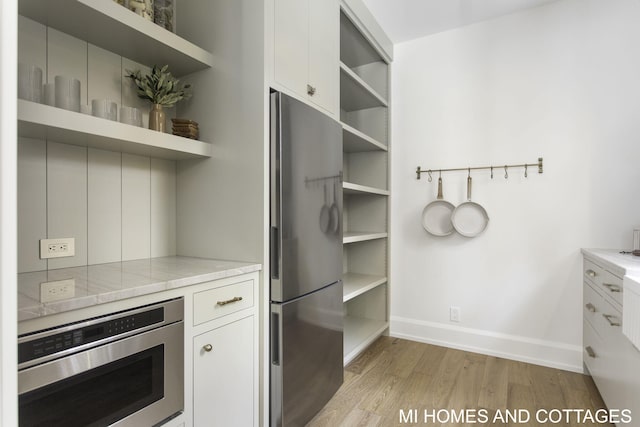 kitchen featuring appliances with stainless steel finishes, light wood-type flooring, and white cabinets