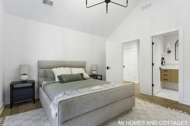 bedroom featuring wood-type flooring, high vaulted ceiling, and ensuite bath