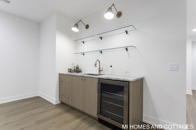 bar featuring wine cooler, sink, and light wood-type flooring