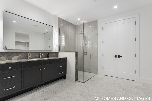 bathroom featuring vanity, decorative backsplash, and a shower with shower door