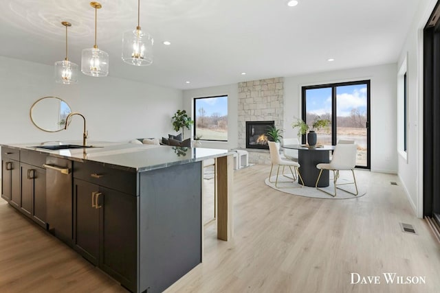 kitchen featuring plenty of natural light, a fireplace, sink, and a center island with sink