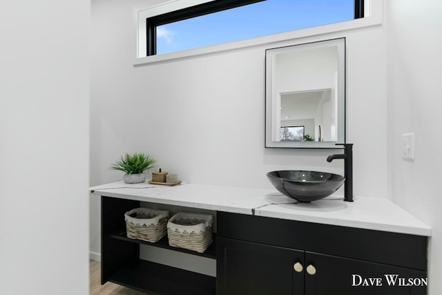 bar featuring light stone counters, sink, and light hardwood / wood-style flooring