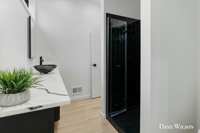 bathroom featuring tiled shower, vanity, and hardwood / wood-style flooring