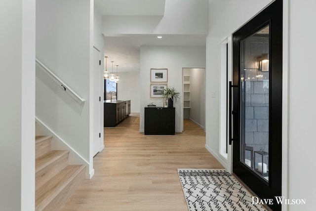 foyer entrance featuring a notable chandelier, light hardwood / wood-style floors, and sink