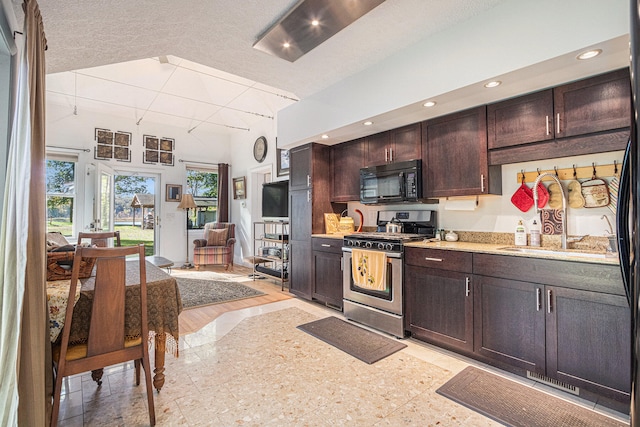 kitchen with gas stove, a textured ceiling, dark brown cabinetry, and light hardwood / wood-style floors