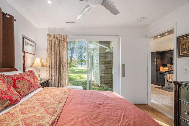 bedroom featuring a textured ceiling, access to exterior, light hardwood / wood-style floors, and ceiling fan