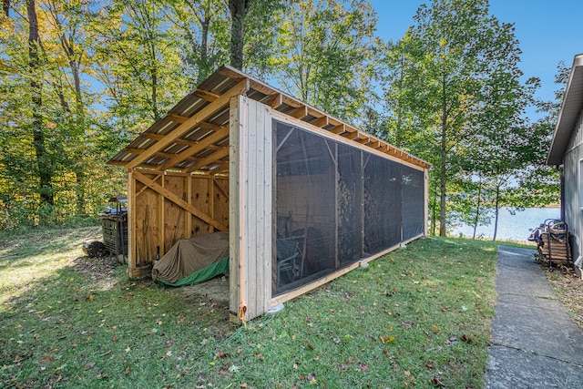 view of outdoor structure with a water view and a lawn