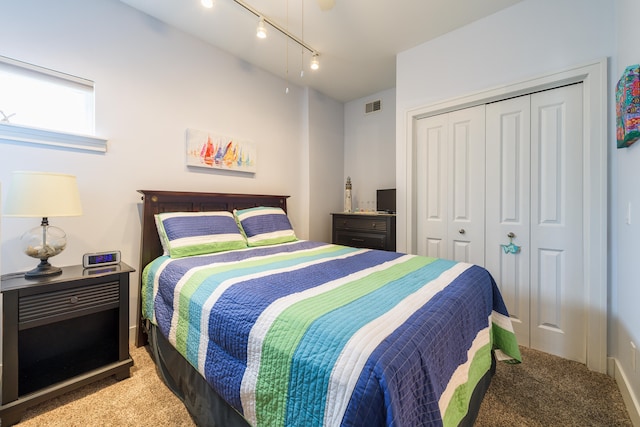 bedroom featuring a closet, carpet flooring, and track lighting