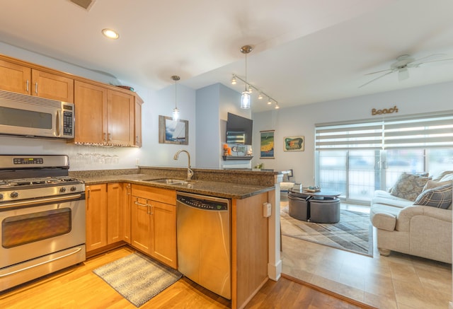 kitchen with appliances with stainless steel finishes, sink, kitchen peninsula, light hardwood / wood-style floors, and decorative light fixtures