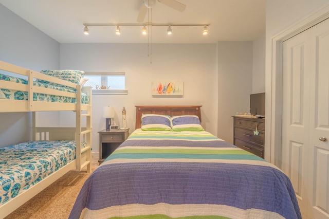 carpeted bedroom featuring a closet, track lighting, and ceiling fan