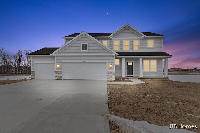 craftsman inspired home featuring driveway, stone siding, and an attached garage