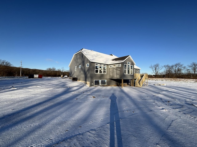 snow covered back of property with a wooden deck