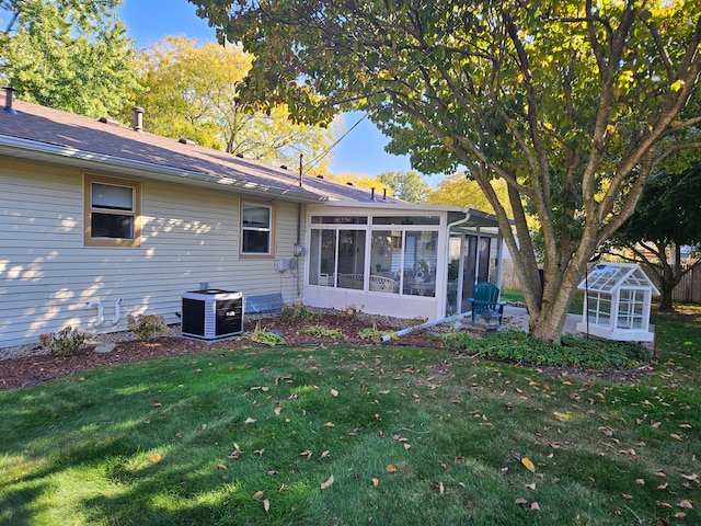 rear view of house featuring a sunroom, a lawn, and cooling unit