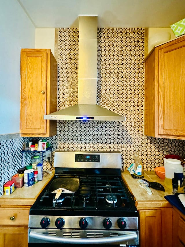 kitchen with stainless steel range with gas stovetop, wall chimney exhaust hood, and decorative backsplash