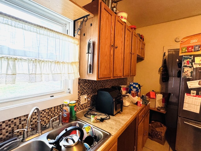 kitchen with decorative backsplash, sink, and stainless steel fridge