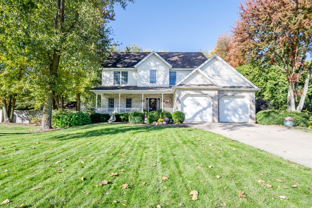 view of front of home featuring a porch, a front lawn, and a garage