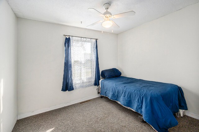 carpeted bedroom with ceiling fan and a textured ceiling