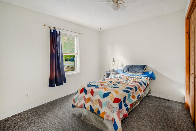 bedroom with dark carpet, a textured ceiling, and ceiling fan