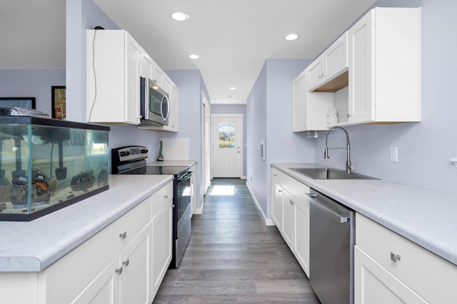 kitchen with white cabinetry, appliances with stainless steel finishes, sink, and hardwood / wood-style floors