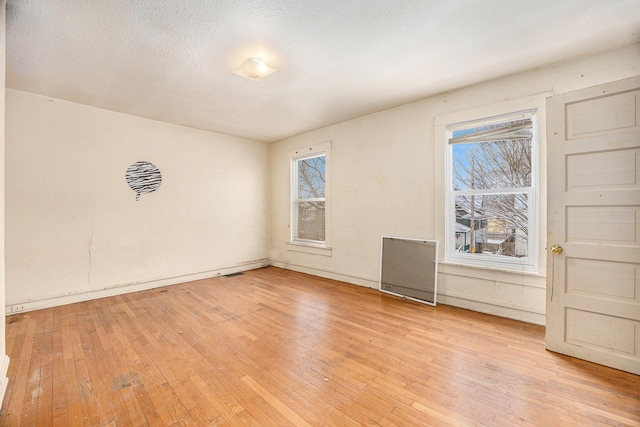 unfurnished room with light hardwood / wood-style floors and a textured ceiling