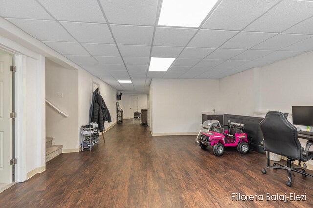 home office with a drop ceiling and dark hardwood / wood-style flooring