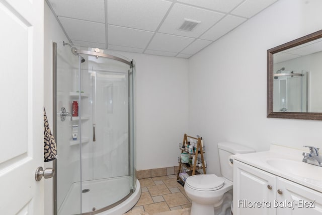 bathroom featuring a drop ceiling, a shower with shower door, toilet, tile patterned floors, and vanity