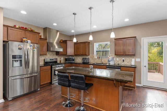 kitchen featuring a kitchen island, wall chimney exhaust hood, stainless steel appliances, sink, and dark hardwood / wood-style flooring