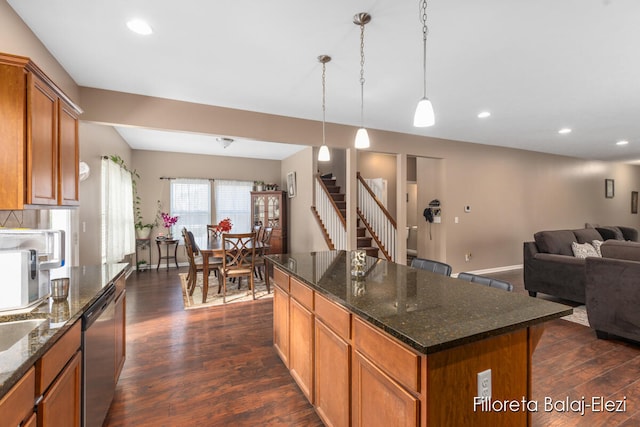 kitchen featuring a kitchen island, dishwasher, dark wood-type flooring, hanging light fixtures, and dark stone counters