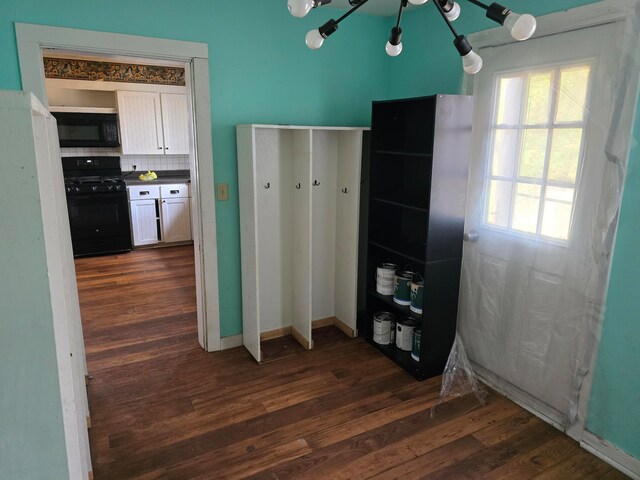 kitchen featuring backsplash, dark hardwood / wood-style flooring, an inviting chandelier, white cabinetry, and black appliances