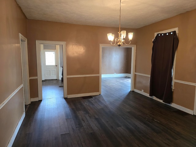 unfurnished dining area featuring a textured ceiling, dark hardwood / wood-style flooring, and an inviting chandelier