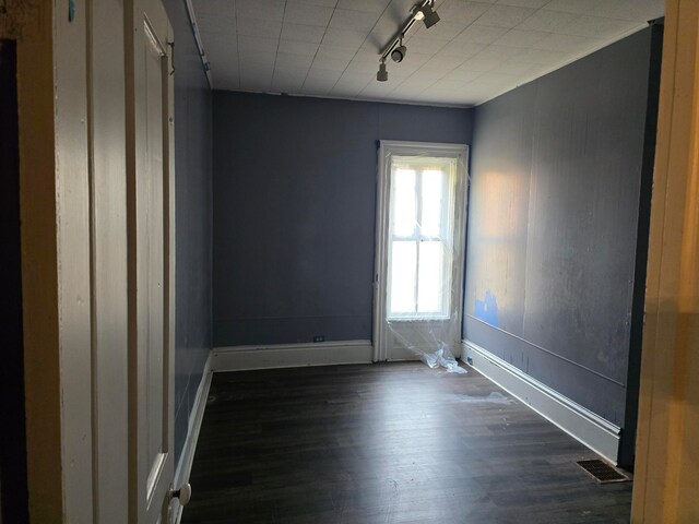 spare room featuring track lighting and dark hardwood / wood-style flooring