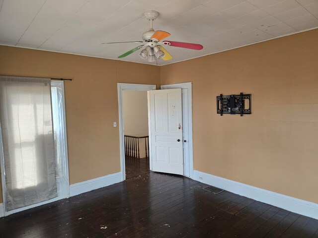 empty room with a wealth of natural light, ceiling fan, and dark hardwood / wood-style flooring