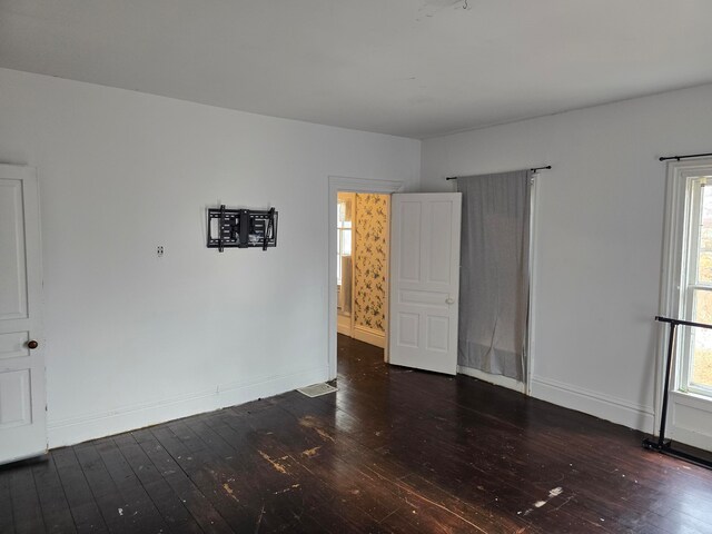 spare room with plenty of natural light and dark hardwood / wood-style flooring