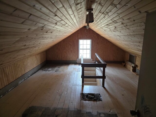 additional living space with hardwood / wood-style floors, wooden walls, vaulted ceiling, and wooden ceiling