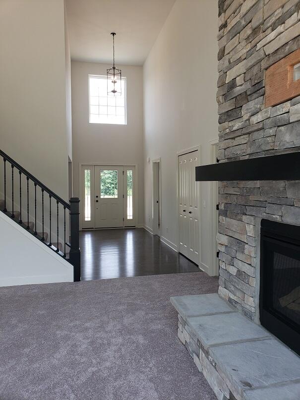 foyer with a fireplace, a towering ceiling, and dark wood-type flooring