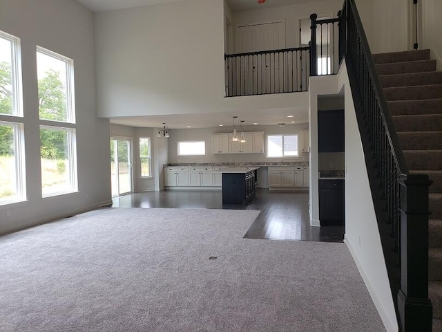 unfurnished living room featuring plenty of natural light, dark hardwood / wood-style floors, and a high ceiling