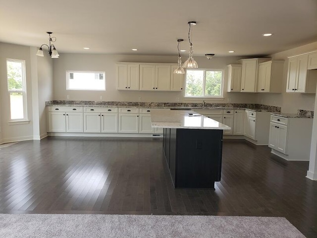 kitchen with pendant lighting, dark hardwood / wood-style flooring, a kitchen island, and a healthy amount of sunlight