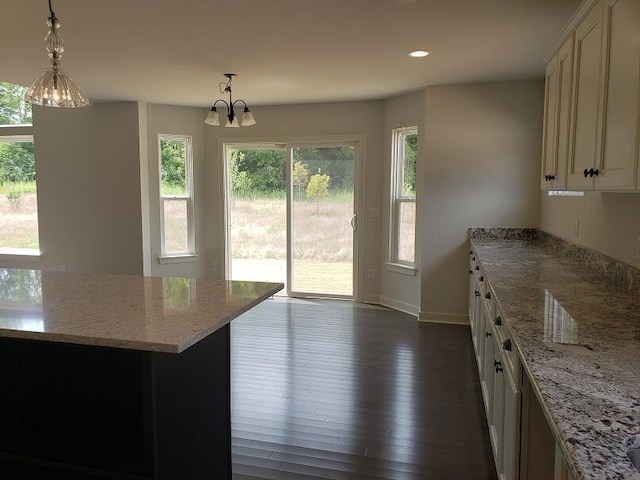 kitchen with light stone counters, dark hardwood / wood-style flooring, hanging light fixtures, and a chandelier