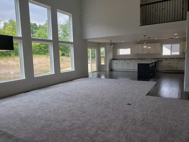 unfurnished living room with a notable chandelier, dark hardwood / wood-style floors, and a high ceiling