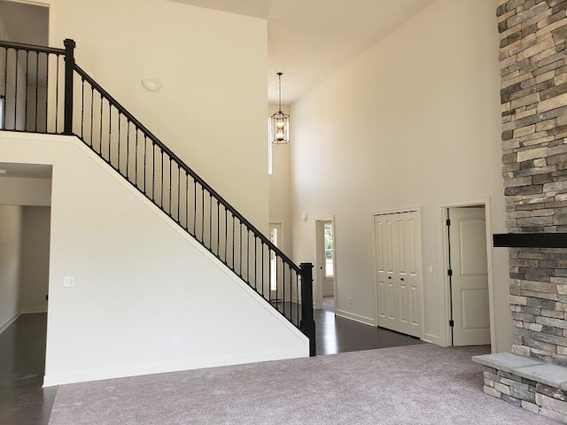 entrance foyer with dark colored carpet and a towering ceiling