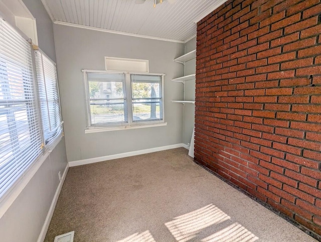 carpeted empty room featuring brick wall and ornamental molding