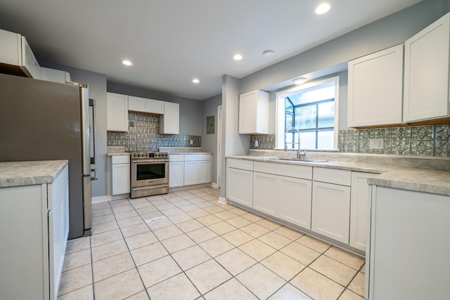 kitchen featuring appliances with stainless steel finishes, sink, backsplash, white cabinets, and light tile patterned floors