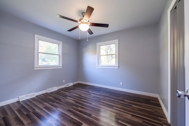 empty room with dark wood-type flooring, ceiling fan, and a healthy amount of sunlight