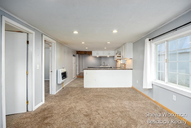 kitchen featuring kitchen peninsula, heating unit, light colored carpet, white cabinets, and a textured ceiling