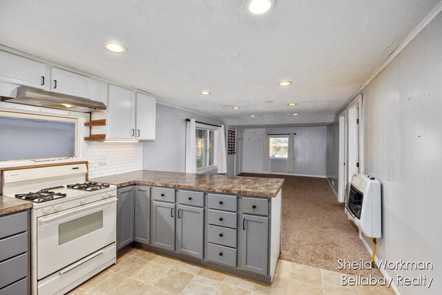 kitchen featuring white range with gas stovetop, white cabinets, heating unit, and kitchen peninsula