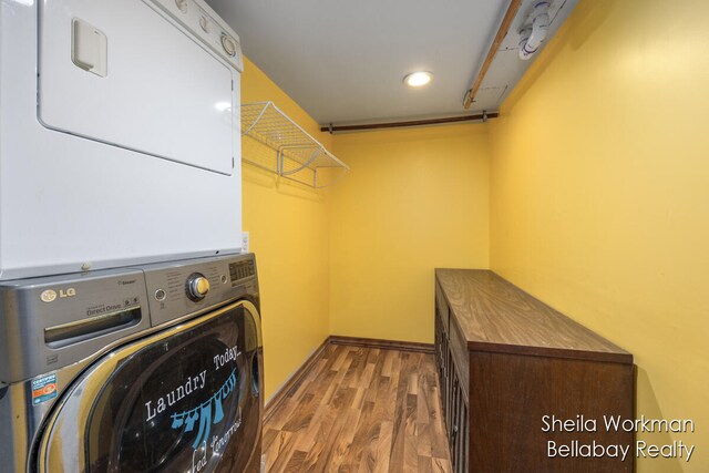 laundry room featuring stacked washer and clothes dryer and wood-type flooring