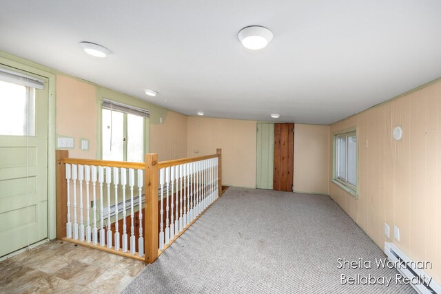 interior space featuring light carpet, a baseboard heating unit, and a wealth of natural light