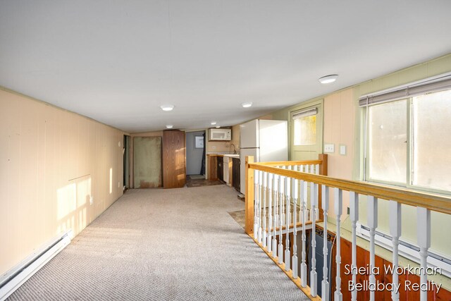 corridor featuring sink, light carpet, and a baseboard heating unit